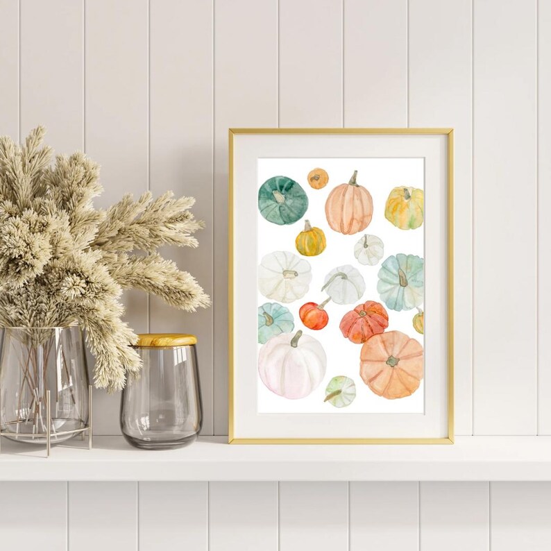 Pode incluir: Uma impress&atilde;o emoldurada com ab&oacute;boras em aquarela em v&aacute;rias cores, incluindo laranja, verde, branco e amarelo. As ab&oacute;boras s&atilde;o dispostas em um fundo branco, criando uma obra de arte com tema de outono. A moldura &eacute; dourada.
