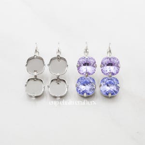 May include: A pair of silver earrings with two square-shaped crystals. The top crystal is a light purple color and the bottom crystal is a light blue color.