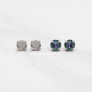 May include: Two pairs of silver stud earrings. One pair has clear settings and the other pair has iridescent green and purple stones.