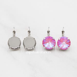 May include: A pair of silver dangle earrings with a round, clear crystal on one side and a round, pink iridescent crystal on the other side.