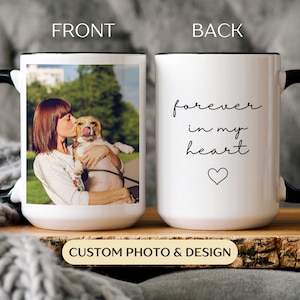 May include: White ceramic mug with a black handle and rim. The front displays a photo of a person kissing a dog. The back of the mug has the words "forever in my heart" with a heart symbol. The bottom of the mug says "CUSTOM PHOTO & DESIGN".