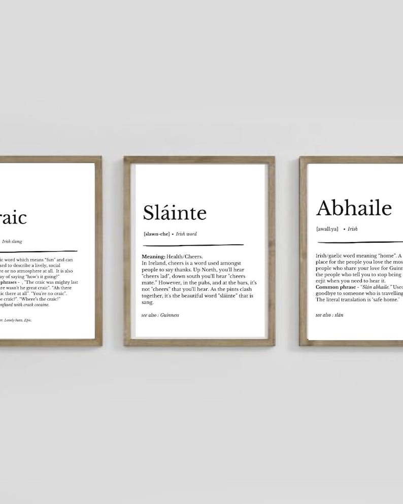 May include: Three framed prints with Irish words and their definitions. The central print displays "Sl&aacute;inte", meaning "Health/Cheers", with its pronunciation. The other prints show "Craic" and "Abhaile", all in a simple, minimalist style.