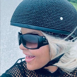 May include: A black motorcycle helmet covered in rhinestones. The helmet has a rounded shape and a smooth, shiny finish. The rhinestones are evenly spaced and create a sparkling effect.