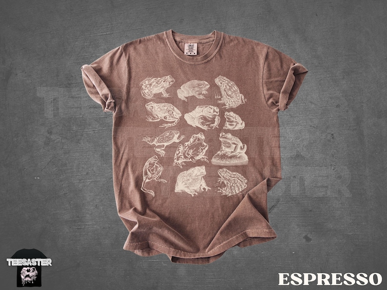Pu&ograve; includere: T-shirt color espresso con illustrazioni bianche di varie specie di rane. La maglietta ha un girocollo e maniche arrotolate. La parola "ESPRESSO" &egrave; stampata in bianco in basso.