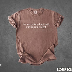May include: Espresso-colored t-shirt with the text "I'm sorry for what I said during game night" in white. The shirt has a crew neck and short sleeves. The shirt is made of a soft material and is displayed on a gray background.