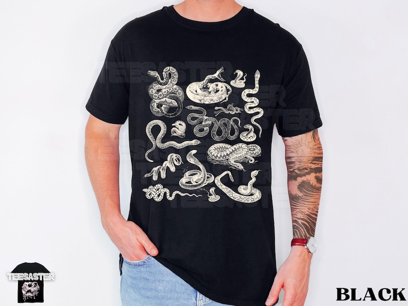 May include: Black t-shirt with a detailed print of various snake illustrations. The snakes are shown in different positions, with a vintage, engraved aesthetic. The word "BLACK" is printed in white, bold letters, indicating the shirt's colour.
