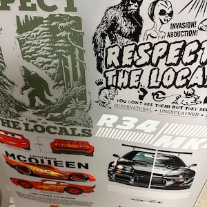 May include: A sheet of stickers featuring various designs. Included are images of Bigfoot, a car, and the text "RESPECT THE LOCALS". Other text includes "INVASION! ABDUCTION!" and "LIGHTNING MCQUEEN". The color palette is primarily black, white, red, and green.