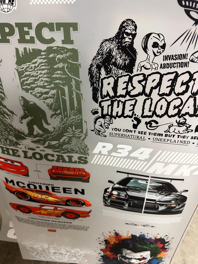 May include: A sheet of stickers featuring various designs. Included are images of Bigfoot, a car, and the text "RESPECT THE LOCALS". Other text includes "INVASION! ABDUCTION!" and "LIGHTNING MCQUEEN". The color palette is primarily black, white, red, and green.