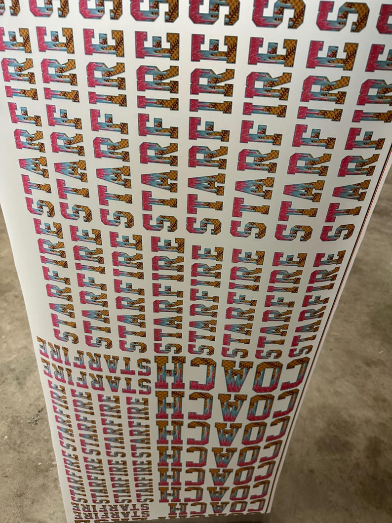 May include: A sheet of printed stickers with the words "STARFIRE" and "COACH" in a repeating pattern. The text is in a bold, stylized font with pink, blue, and gold accents. The background is white.
