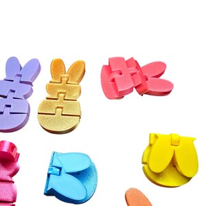 Könnte beinhalten: Ein Set aus sieben bunten Hasen-Anhängern. Die Anhänger sind aus einem weichen, biegsamen Material gefertigt und eignen sich perfekt, um jedem Raum einen Hauch von Verspieltheit zu verleihen.