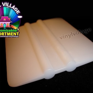 Puede incluir: Rasqueta de plástico blanco con dos bordes redondeados. La rasqueta se utiliza para alisar las pegatinas y calcomanías de vinilo.