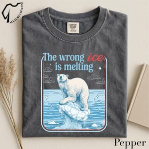 a gray t-shirt with a graphic design depicting a polar bear on an ice floe, accompanied by the text "The wrong ice is melting".