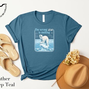 a blue t-shirt with a graphic of a polar bear, a pair of flip-flops, a hat, and some flowers arranged on a white background.