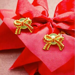 May include: Two red fabric gift bags with gold bows. The bows have red and gold accents.