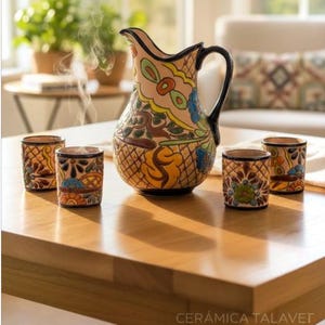 May include: A ceramic pitcher and four matching small cups featuring hand-painted floral and geometric patterns in yellow, blue, green, and brown on a cream background. The pitcher has a dark handle and the text CERÁMICA TALAVET is visible.