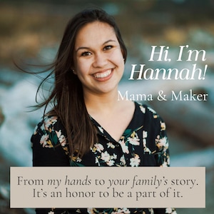 May include: A smiling woman with long brown hair is featured in a portrait. The text "Hi, I'm Hannah! Mama & Maker" is displayed above her. Below, a banner reads, "From my hands to your family's story. It's an honor to be a part of it."