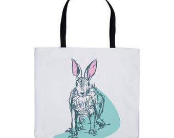 May include: A white tote bag with a black handle and a drawing of a rabbit with pink ears on a teal blue background.
