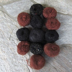 May include: A collection of yarn balls in black and brown shades. Some of the balls have a sparkly finish.