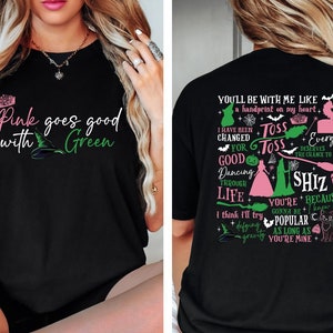 May include: Black t-shirt with a pink and green graphic print. The front of the shirt says "Pink goes good with Green". The back of the shirt has a graphic print with the text "You'll be with me like a handprint on my heart. I have been changed for good. Toss Toss Everyone deserves the chance to fly. Dancing through life. I think I'll try. You're gonna be popular as long as you're mine. Shiz because I knew you."