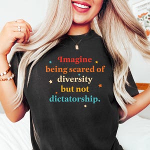 May include: A black t-shirt with a retro-style graphic that reads "Imagine being scared of diversity but not dictatorship."