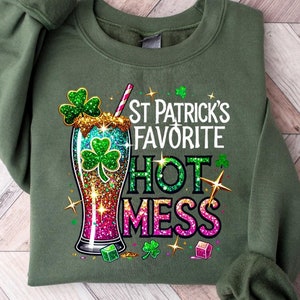 Peut inclure: Sweat-shirt vert avec un graphique représentant un trèfle vert et un verre de liquide vert, rose et bleu avec le texte "St. Patrick's Favorite Hot Mess".