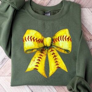 K&ouml;nnte beinhalten: Ein gr&uuml;nes Sweatshirt mit einem gelben und roten Softball-Schleifendesign.