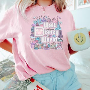 May include: Pink t-shirt with a graphic design of various Disney World attractions and the text "Walt Disney World".