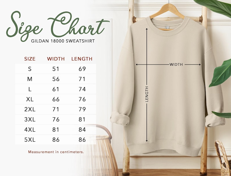 May include: A beige Gildan 18000 sweatshirt displayed on a wooden hanger. The image includes a size chart with measurements in centimeters, detailing width and length for sizes S through 5XL. The sweatshirt is shown with length and width indicators.