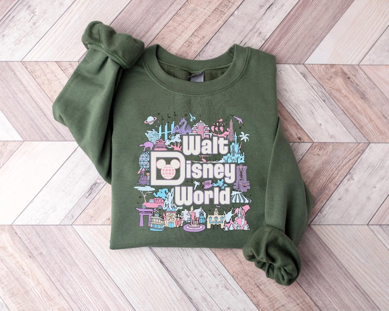 May include: A green sweatshirt with a colorful graphic of Walt Disney World landmarks and the text "Walt Disney World".