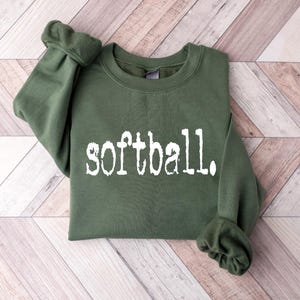 K&ouml;nnte beinhalten: Ein gr&uuml;ner Pullover mit dem Wort "Softball" in wei&szlig; auf der Vorderseite.