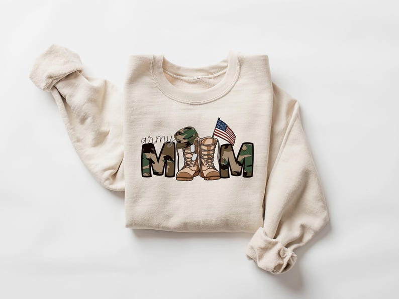 May include: A beige sweatshirt with a camouflage print that reads "army mom" with a pair of boots and a small American flag.