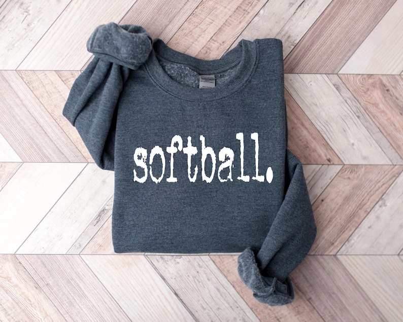 K&ouml;nnte beinhalten: Ein dunkelgrauer Pullover mit dem Wort "Softball" in wei&szlig; auf der Vorderseite.