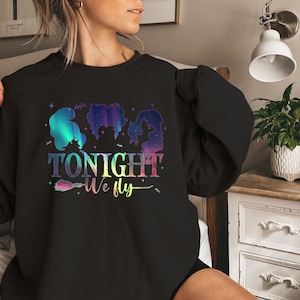 May include: Black sweatshirt with a colorful graphic featuring three witch silhouettes and the text "TONIGHT We fly". The design includes a broom and stars, with a gradient color scheme.