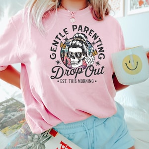 Puede incluir: Camiseta rosa con un gr&aacute;fico de una calavera con gafas de sol y un mo&ntilde;o con el texto "Gentle Parenting Drop Out - Est. This Morning."