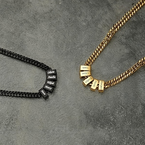 May include: Two necklaces with personalized name beads. One necklace is black with black beads, the other is gold with gold beads. The black necklace has the names Olivia, Amelia, Elijah, Henry, and Nora. The gold necklace has the names Liam, Chloe, Evelyn, Jacob, and Harper.