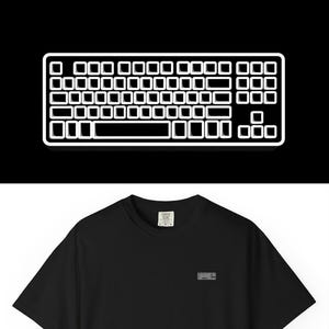 Può includere: T-shirt nero con una piccola etichetta rettangolare sul petto. Sopra la maglietta c'è un contorno bianco di una tastiera su sfondo nero. La maglietta è a maniche corte e ha un girocollo.