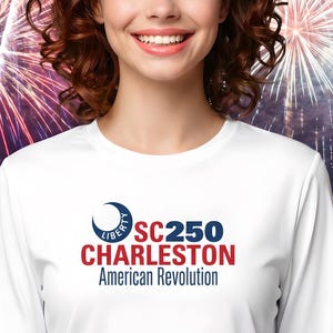 May include: A woman wearing a white long-sleeved top with the text "SC250 Charleston American Revolution" in red and blue. The background shows fireworks and a waterfront scene.