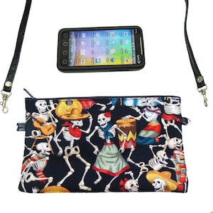 May include: A black zippered pouch with a colorful print of skeletons dancing and playing musical instruments. The pouch has a black adjustable strap and a silver zipper pull.