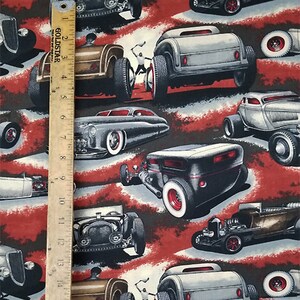 May include: A red, white, and blue fabric with a repeating pattern of vintage hot rods. The hot rods are in various colors, including black, gray, and blue. The fabric is perfect for quilting, crafts, and home decor.