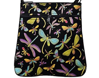 May include: Black crossbody bag with a colorful dragonfly pattern. The bag features a zippered main compartment and a smaller front zippered pocket. The dragonflies are in shades of yellow, purple, blue, and orange.