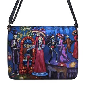 May include: A rectangular crossbody bag with a black strap. The bag features a vibrant illustration of skeletons in festive attire, set against a dark blue background. The artwork depicts a lively scene with buildings and floral decorations.