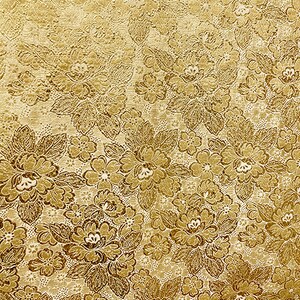 May include: A close-up view of a golden floral pattern. The design features large, detailed flowers and smaller blossoms, creating a textured, repeating motif. The color palette includes shades of gold and brown, with a subtle gradient effect.