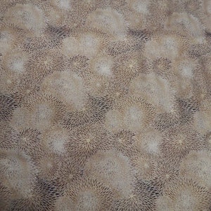 May include: Close-up of a light brown surface with a repeating pattern of small, white, starburst-shaped designs.