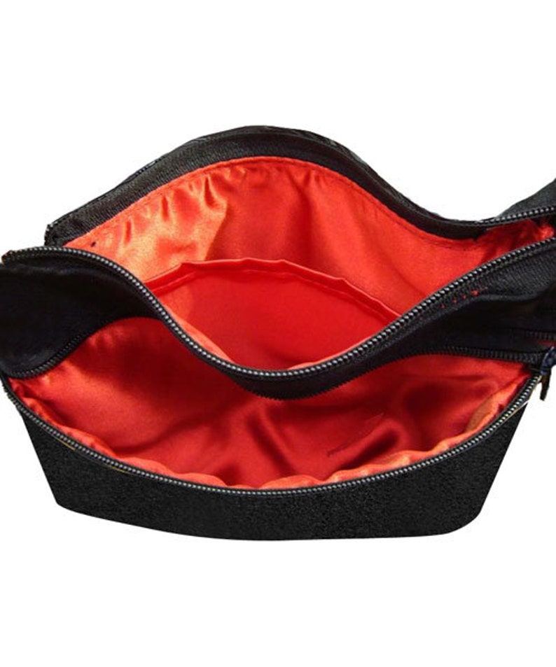 K&ouml;nnte beinhalten: Schwarze Rei&szlig;verschlusstasche mit rotem Satin-Futter. Die Tasche hat zwei F&auml;cher.