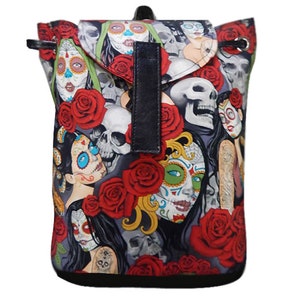 May include: A small, drawstring backpack featuring a Day of the Dead design. The bag is covered in images of sugar skulls, red roses, and other related imagery. The bag has a black flap and strap closure.