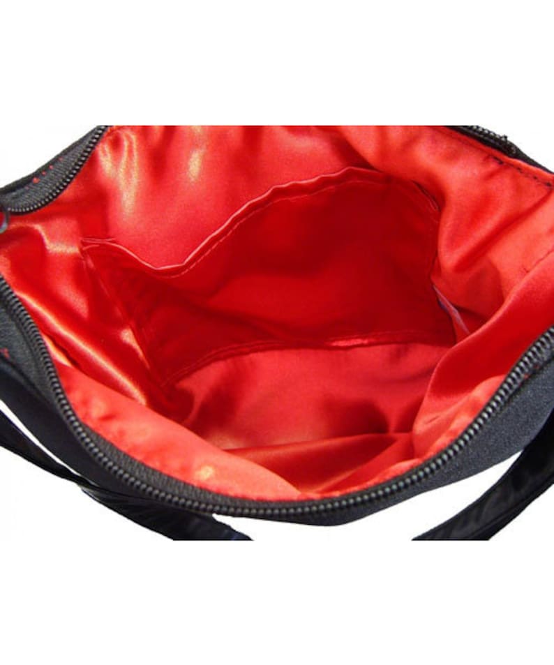 K&ouml;nnte beinhalten: Eine schwarze Tasche mit Rei&szlig;verschluss und roter Satinfutter. Die Tasche hat eine kleine Innentasche.