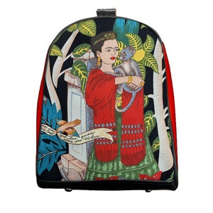 Può includere: Zaino rosso con un davanti in tela nera che presenta un'illustrazione colorata di Frida Kahlo che tiene una scimmia. L'illustrazione include un uccello, piante e il testo "Pies para volar".