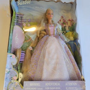 Puede incluir: Una muñeca Barbie con cabello largo rubio que viste un vestido lavanda y rosa con detalles dorados, empaquetada en una caja con un cepillo para el cabello morado. El empaque incluye texto como Barbie, Rapunzel y advertencias de seguridad.