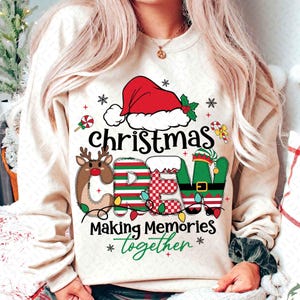 Może przedstawiać: Kremowa bluza z świątecznym motywem bożonarodzeniowym. Projekt zawiera czapkę Świętego Mikołaja, renifery i elementy elfów, które tworzą napis "CREW". Tekst "Making Memories Together" jest również obecny, z płatkami śniegu i akcentami lasek cukrowych.