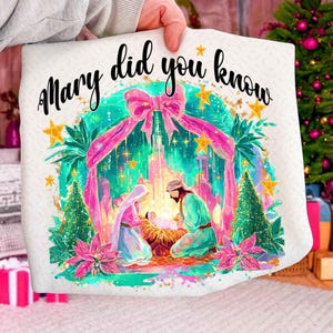 May include: A white pillow with a colorful illustration of the Nativity scene, featuring Mary, Joseph, and baby Jesus. The text "Mary did you know" is written in black script above the scene. The design includes pink, green, and gold accents.
